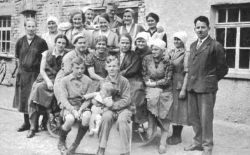 Eröffnung Zweigbetrieb in Rot a. d. Rot. Schwarz-weiß Gruppenfoto von Männern und Frauen in Arbeitskleidung vor einem Gebäude.
