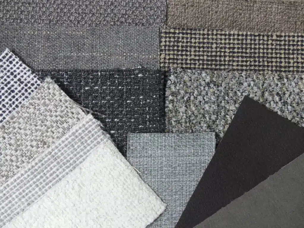 Verschiedenfarbige Polsterstoffe in unterschiedlichen Webarten, dicht nebeneinandergelegt.