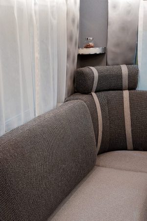 Vorhänge in Grau- und Beigetönen neben einer gepolsterten Sitzecke mit passenden Farbakzenten.